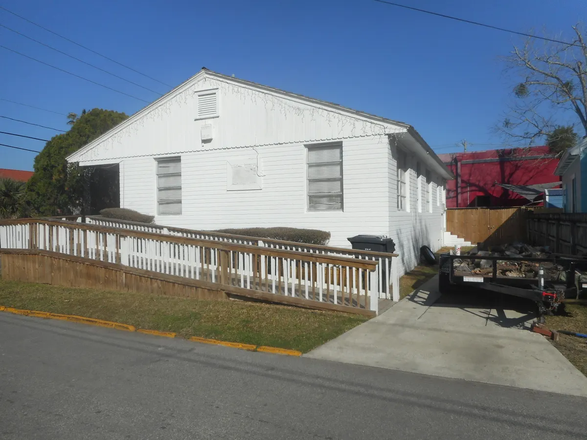 A long wooden ramp with a white picket rail running along the side of a white clapboard building.